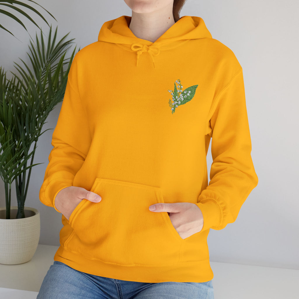 Gold hooded sweatshirt with green leaf embroidery, front view, hands in pocket