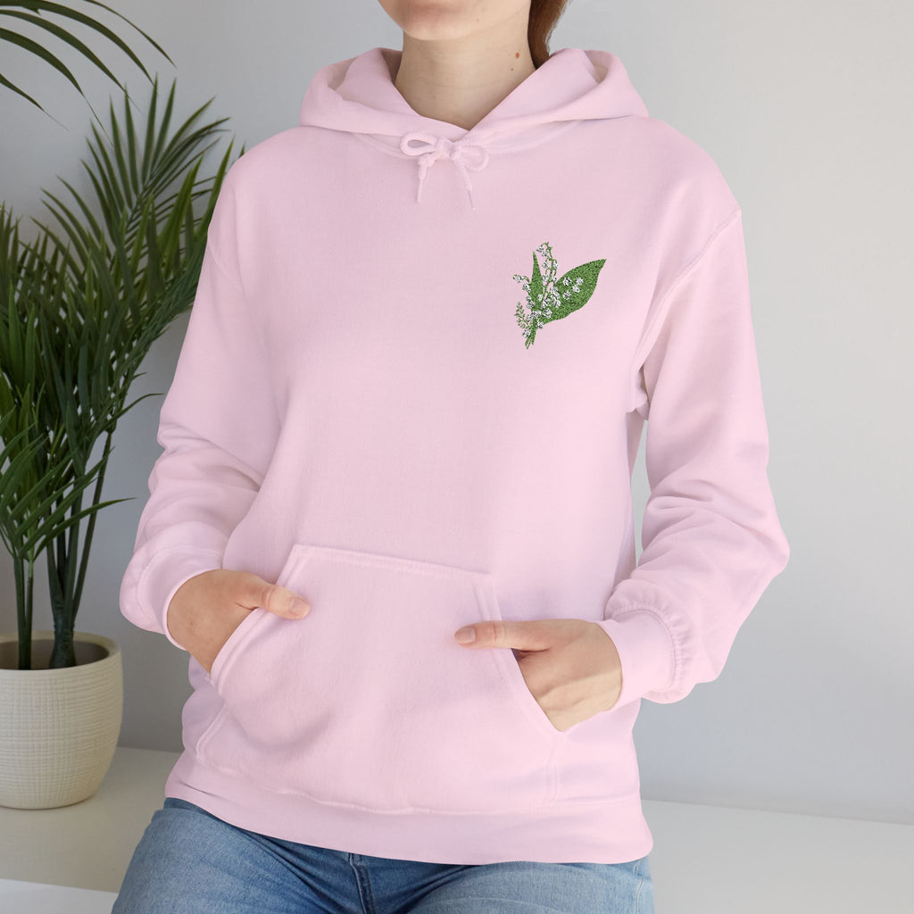 Light pink hoodie with green leaf embroidery on chest and drawstring hood, close-up