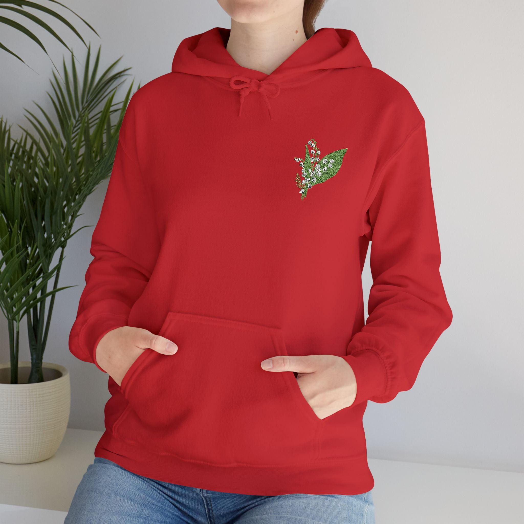 Red hoodie close-up: green leaf embroidery, drawstring hood, front kangaroo pocket