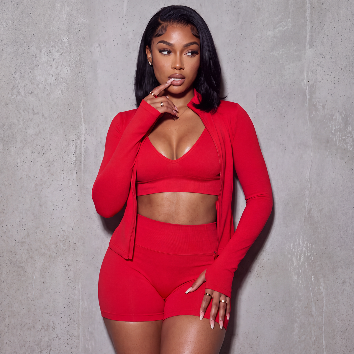 Women’s red 3-piece active set: V-neck sports bra, high-waist shorts, zip jacket with thumb holes.