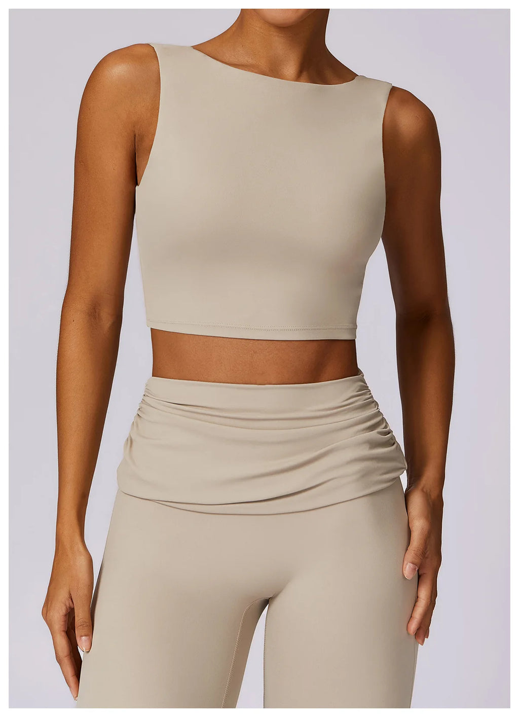 Beige sleeveless sports bra crop top with smooth front and stitched neckline.