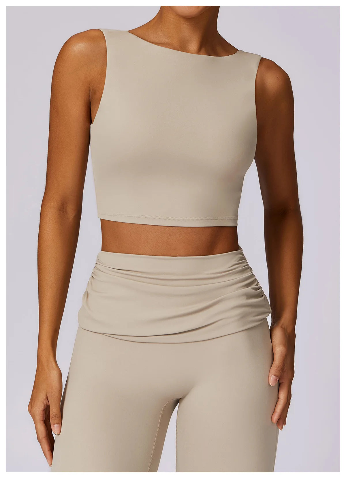 Beige sleeveless sports bra crop top with smooth front and stitched neckline.