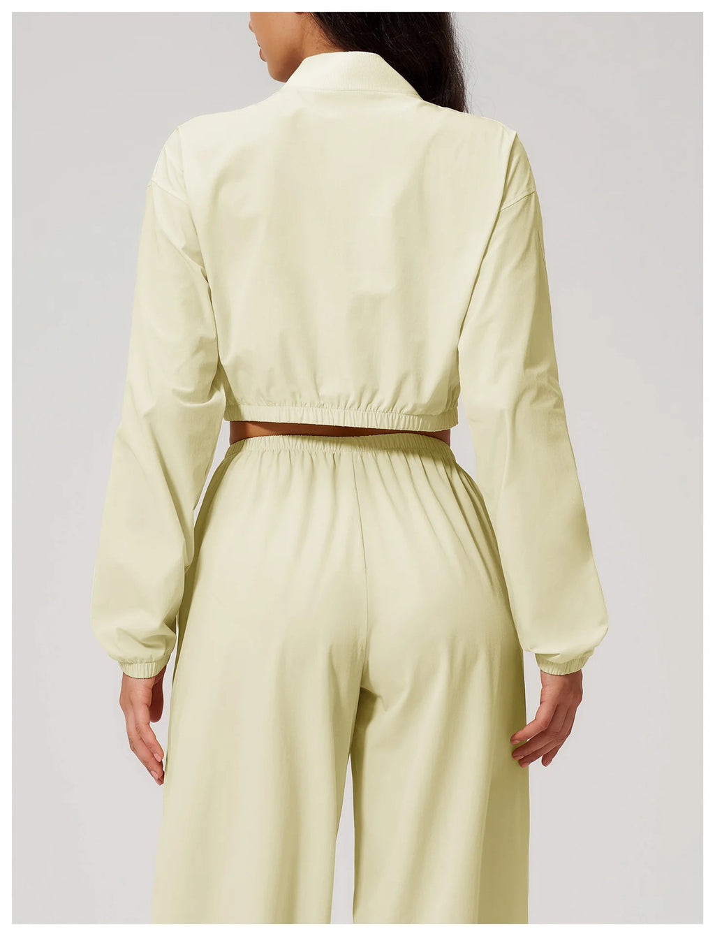 Women’s almond yellow cropped zip-up jacket, back view with elastic hem.