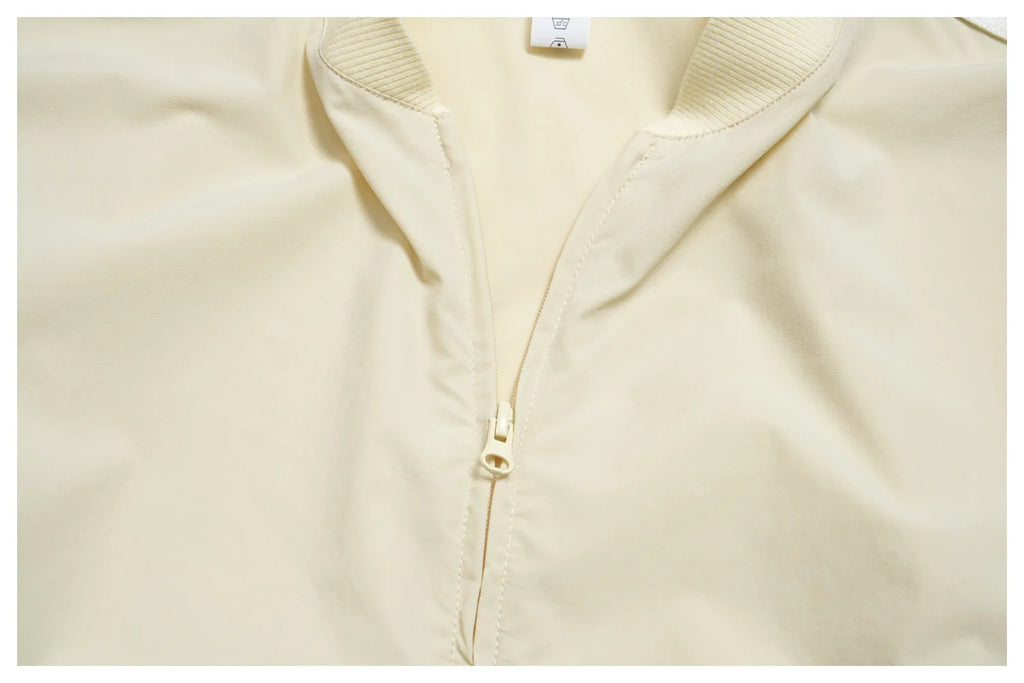 Women’s zip-up athletic jacket, light cream front with centered gold zipper
