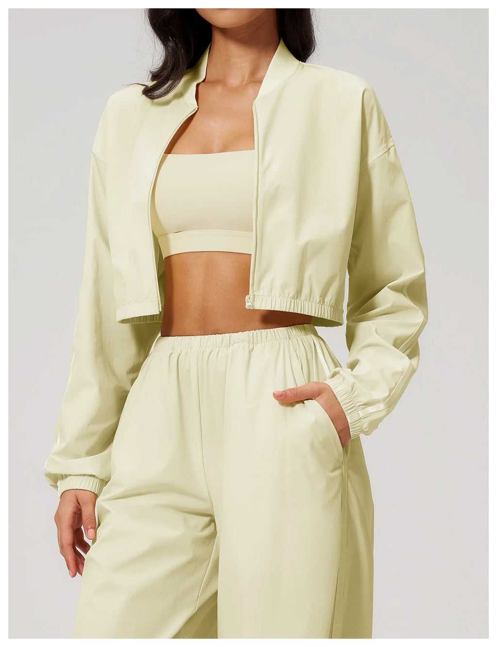 Women’s almond yellow cropped zip-up jacket with long sleeves and elastic waist hem.