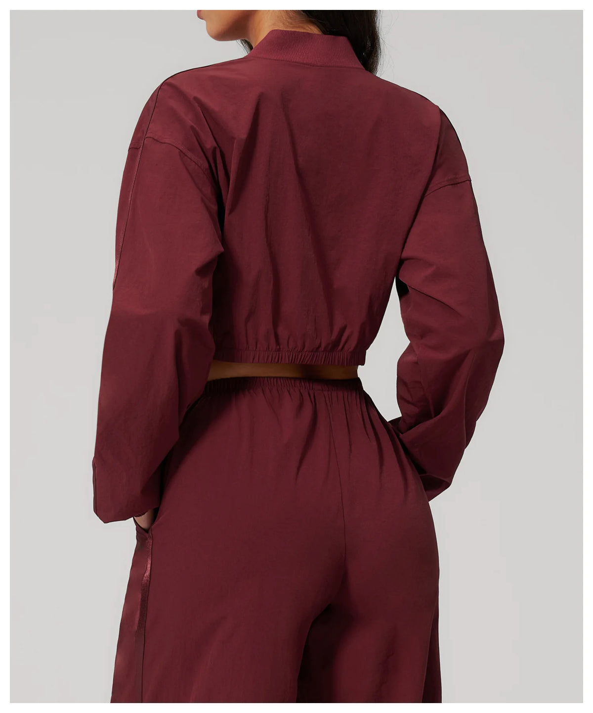 Women’s cropped yoga jacket in deep maroon, back view with gathered hem