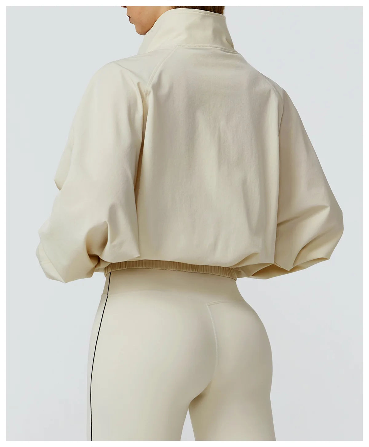 Back view of Xooie Fit women's windproof fitness jacket in cream color with a cropped design