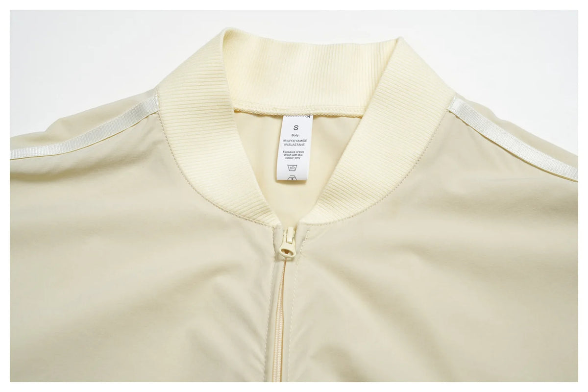 Women’s zip-up athletic jacket, light cream with stand collar and gold zipper