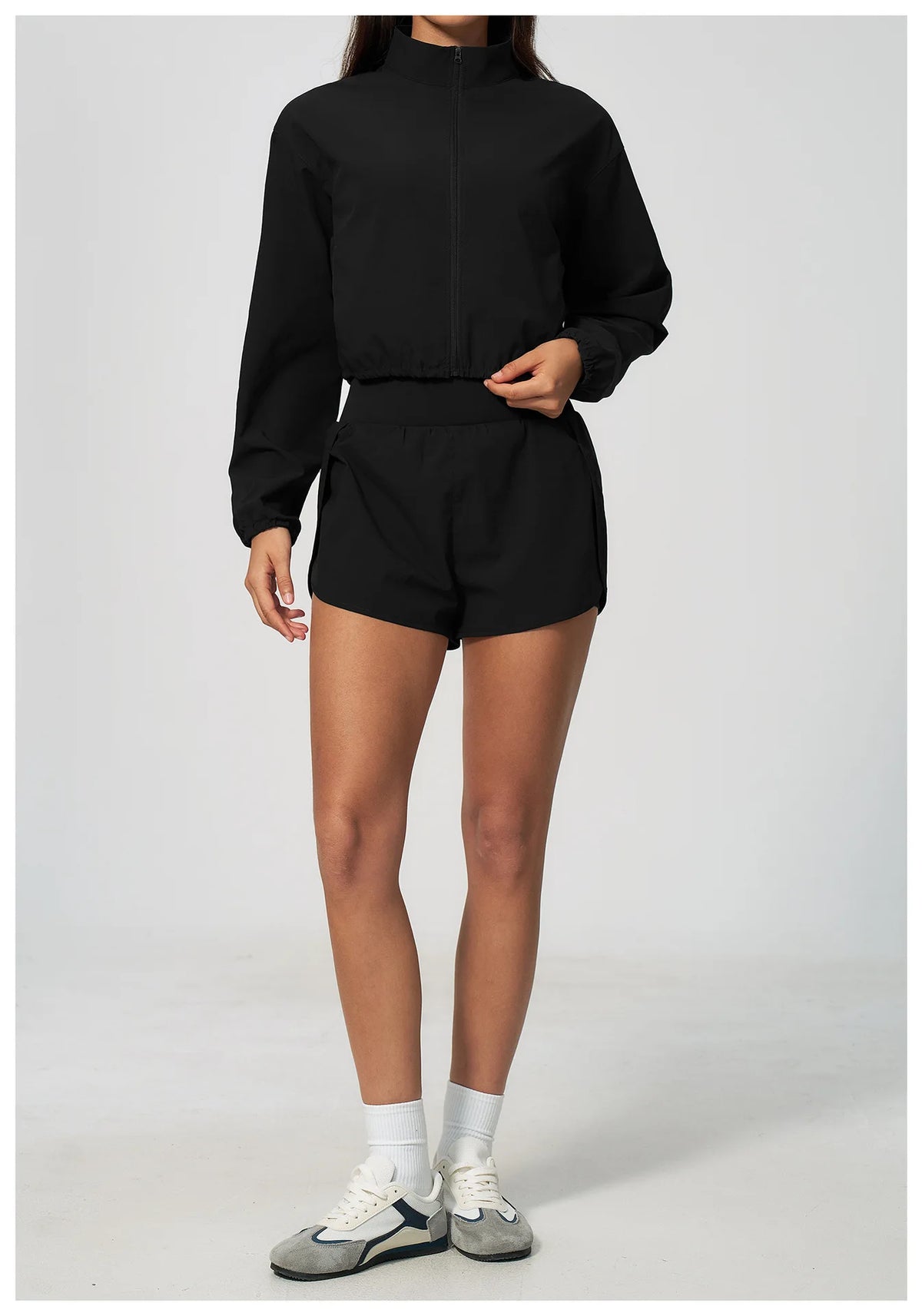 Black zip-up long sleeve workout jacket with elastic waistband and high collar