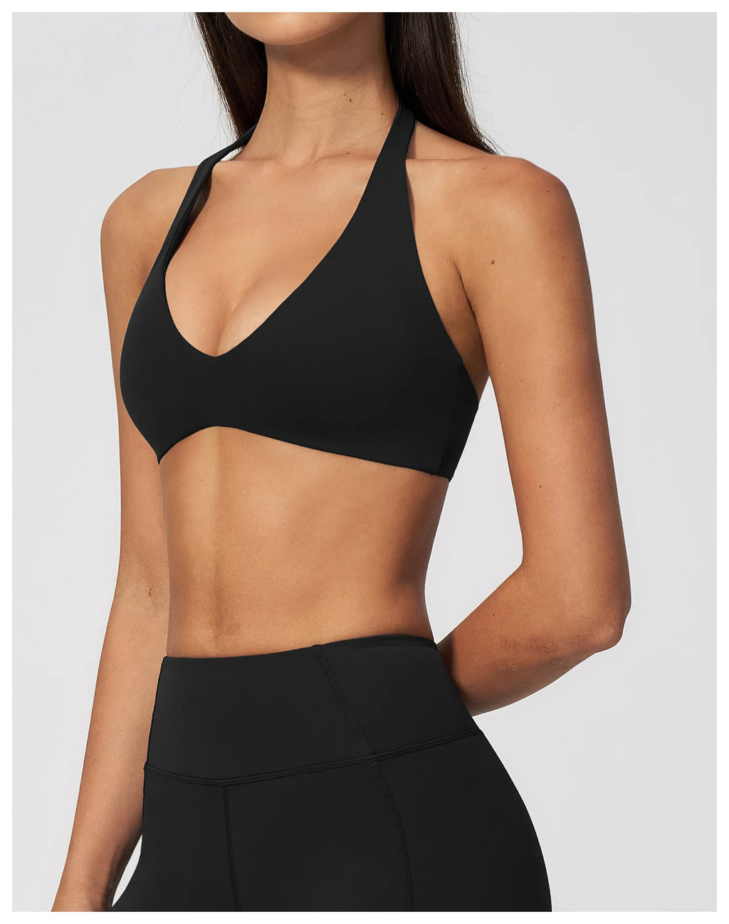 Black halter neck sports bra with deep V neckline, sleeveless cropped gym top