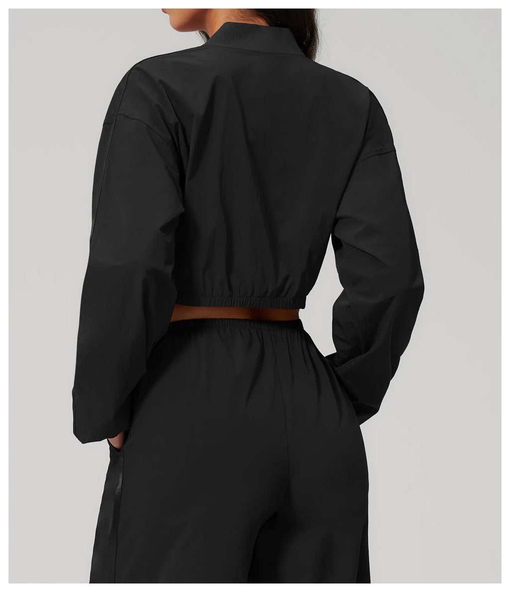 Women’s cropped yoga jacket in black, back view with gathered elastic waist