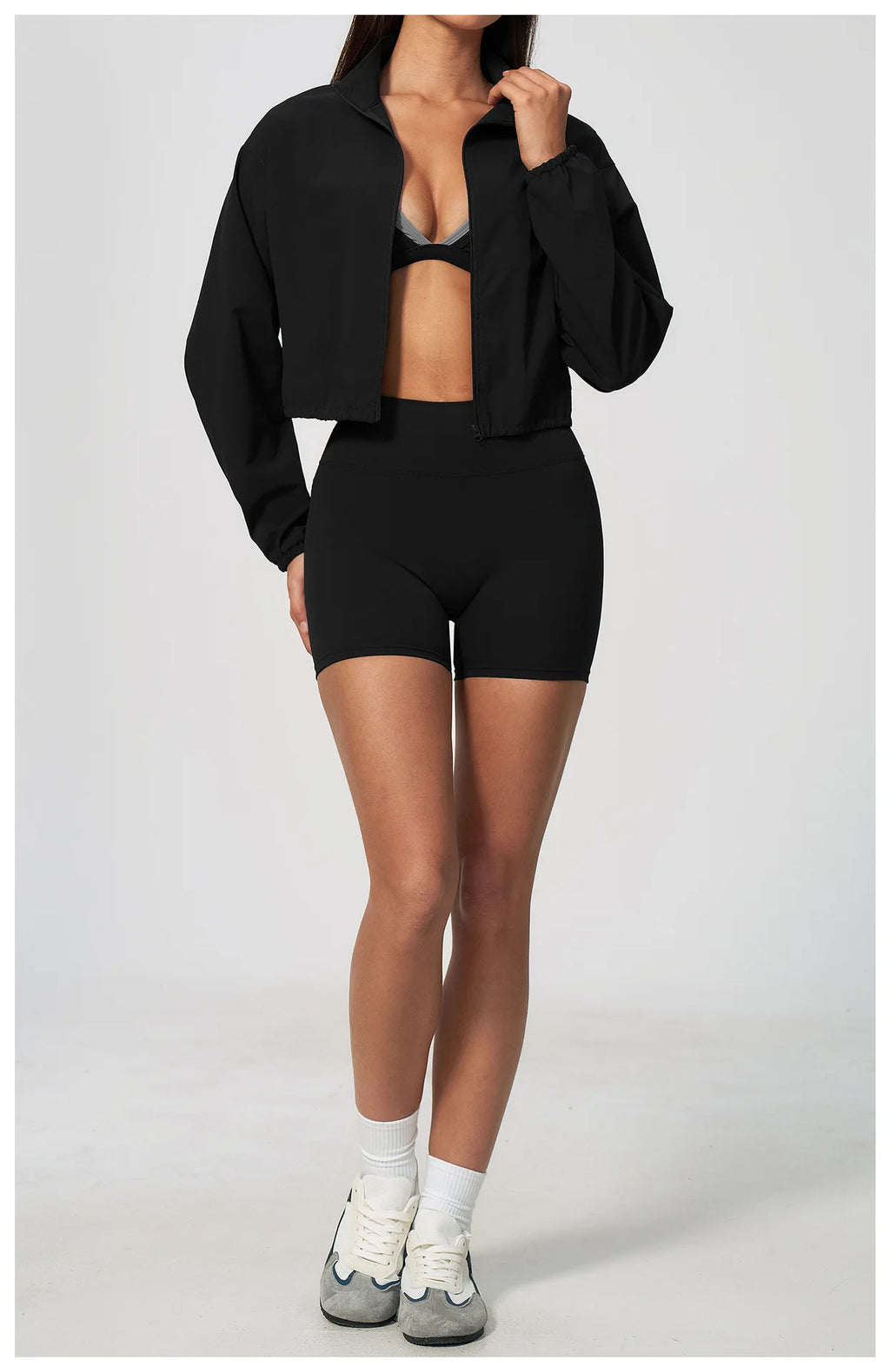Black zip-up athletic jacket with long sleeves, open front, elastic waist
