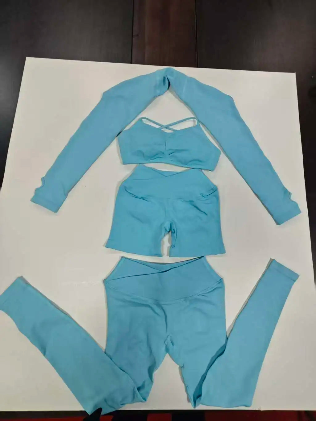Aqua blue seamless workout set flat lay: shrug, sports bra and leggings