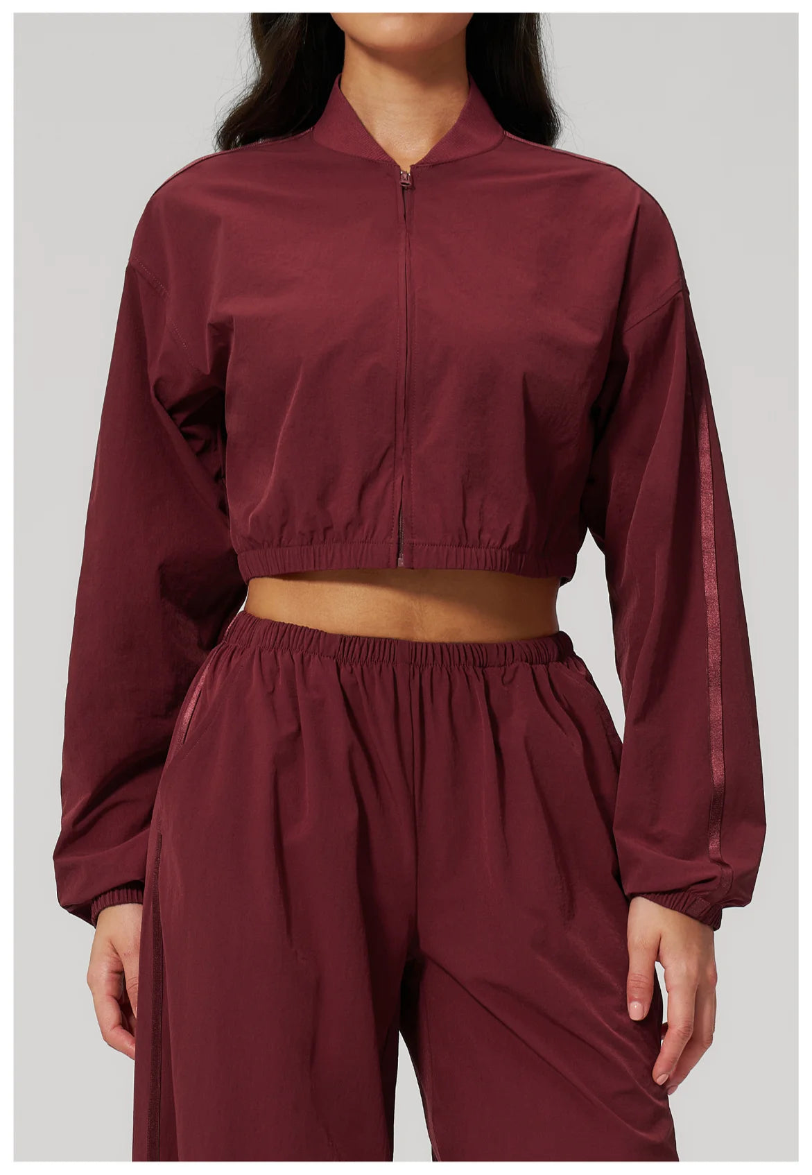 Women’s cropped cherry red zip-up jacket with long sleeves and elastic cuffs.