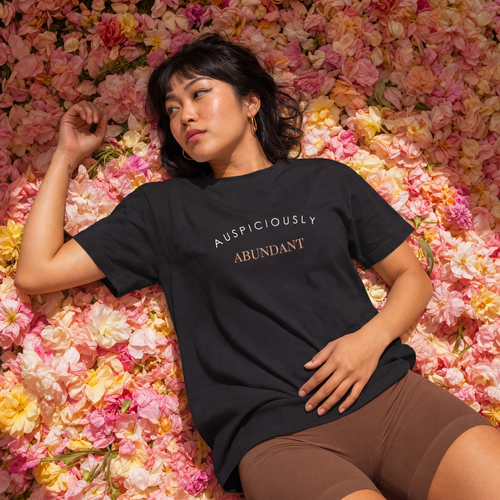 Black crewneck T-shirt with “AUSPICIOUSLY ABUNDANT” text graphic on the front.