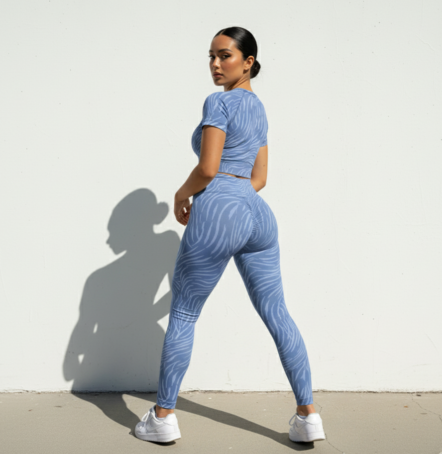 Woman in blue patterned athletic outfit standing against a white wall