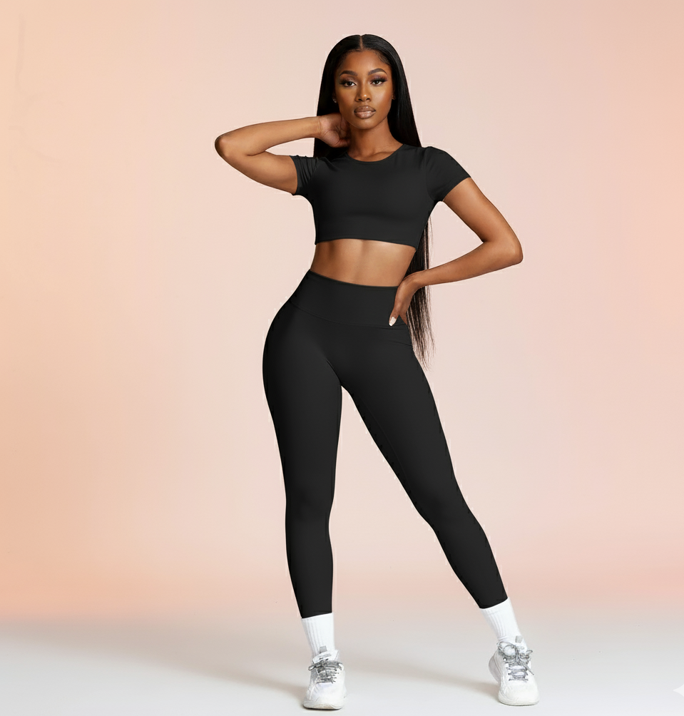 Woman wearing a black athletic outfit on a light pink background