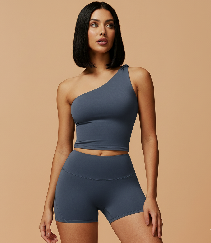 Woman wearing a blue one-shoulder top and shorts on a beige background