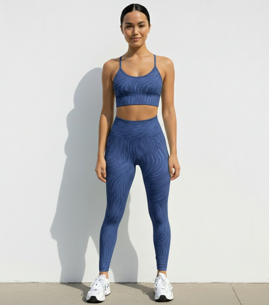 Woman wearing a blue zebra  athletic outfit standing against a white wall.