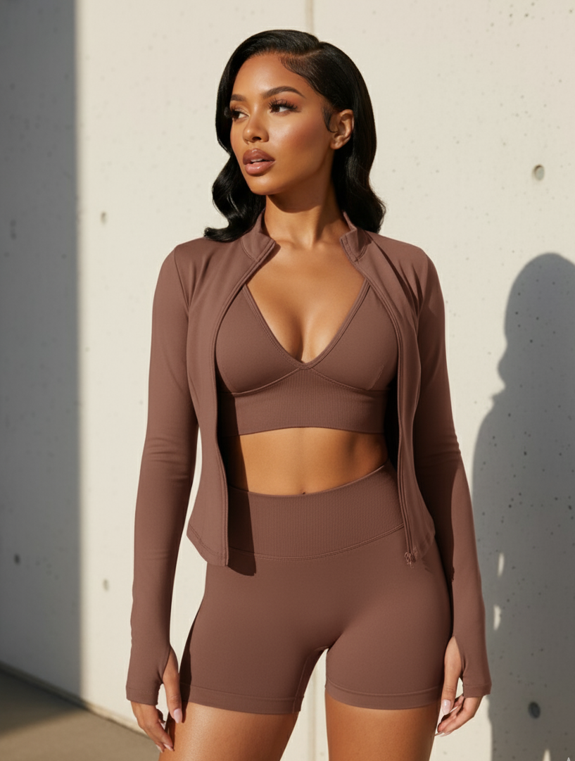 Woman wearing a brown athletic outfit against a light-colored wall.