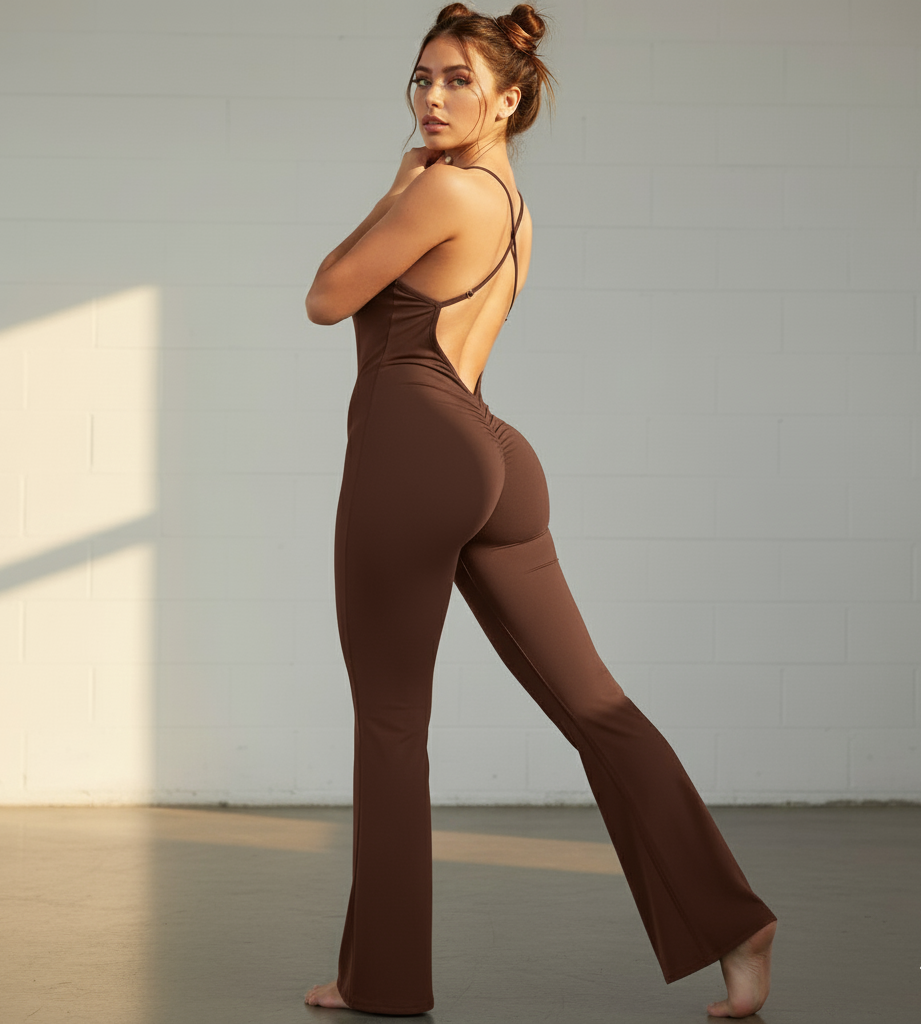 Woman wearing a brown jumpsuit with a backless design, standing against a neutral background.