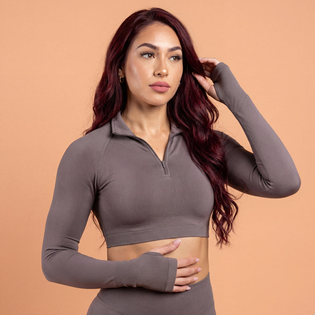 Woman wearing a brown long-sleeve athletic top against a beige background