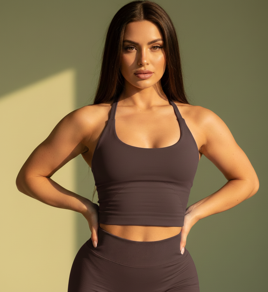 Woman wearing a brown sports bra and leggings against a green background