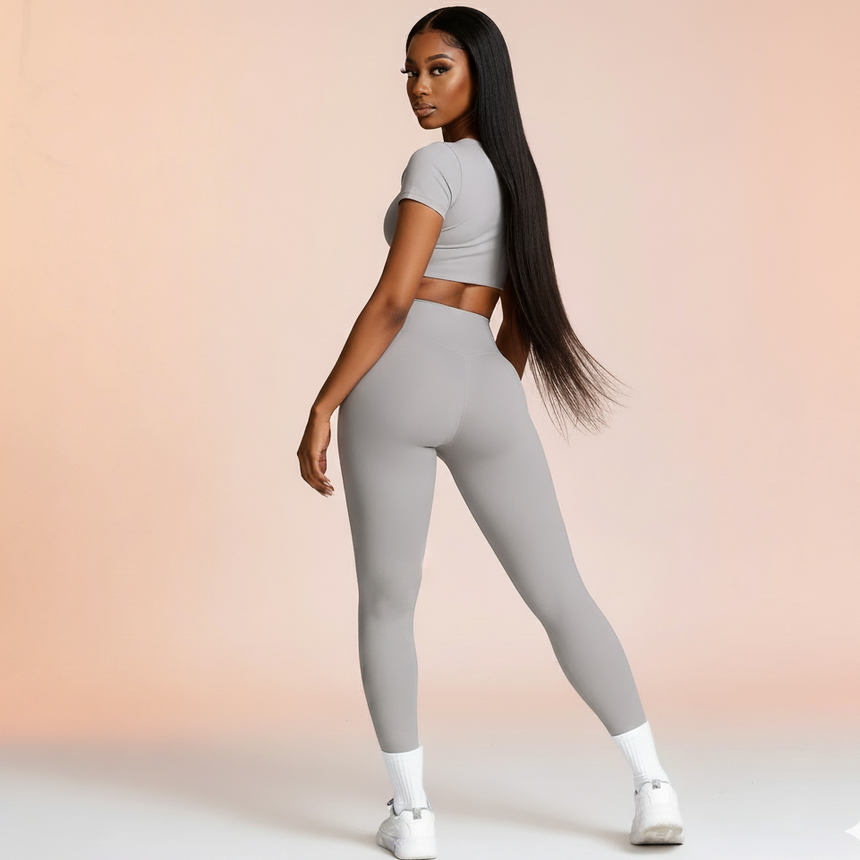 Woman wearing a gray athletic outfit on a gradient background