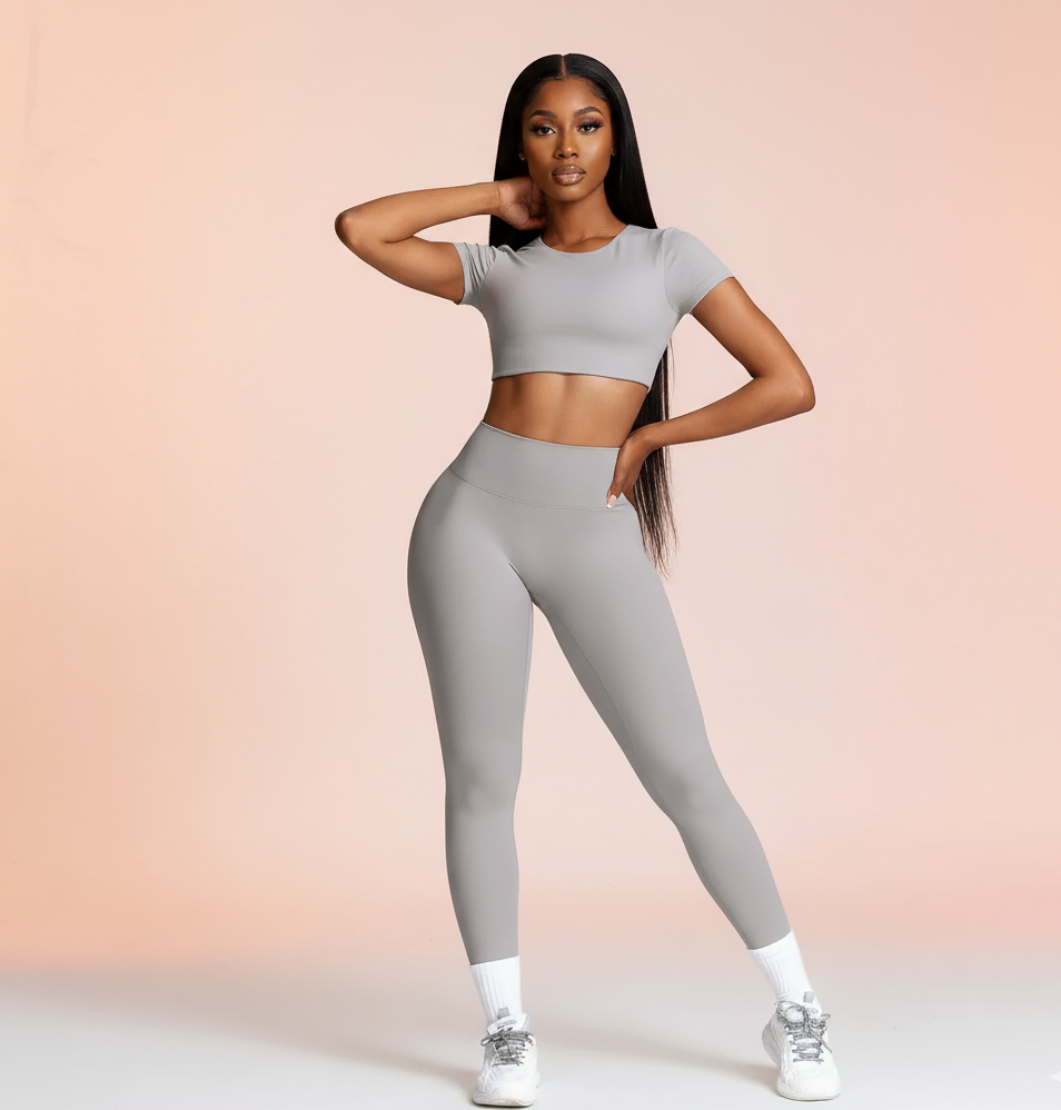 Woman wearing a gray athletic outfit on a light pink background