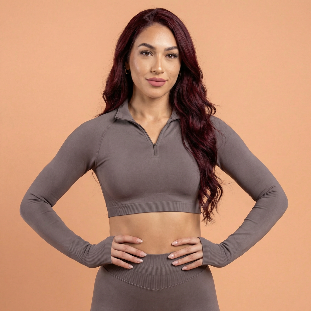 Woman wearing a gray long-sleeve athletic top on a peach background