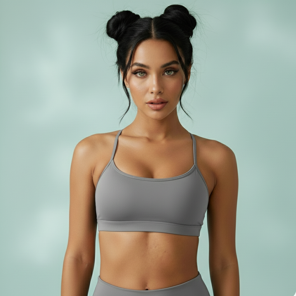 Woman wearing a gray sports bra and leggings against a light green background