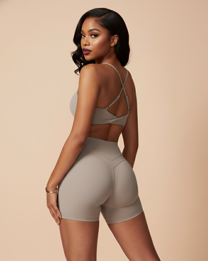 Woman wearing a gray sports bra and shorts on a beige background