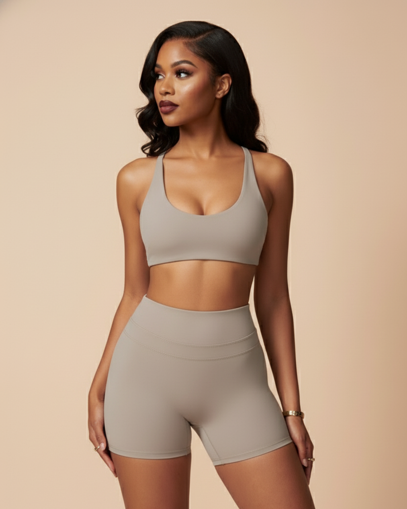 Woman wearing a gray sports bra and shorts set on a beige background