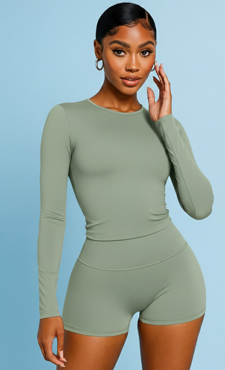 Woman wearing a green long-sleeve top and shorts set on a light blue background