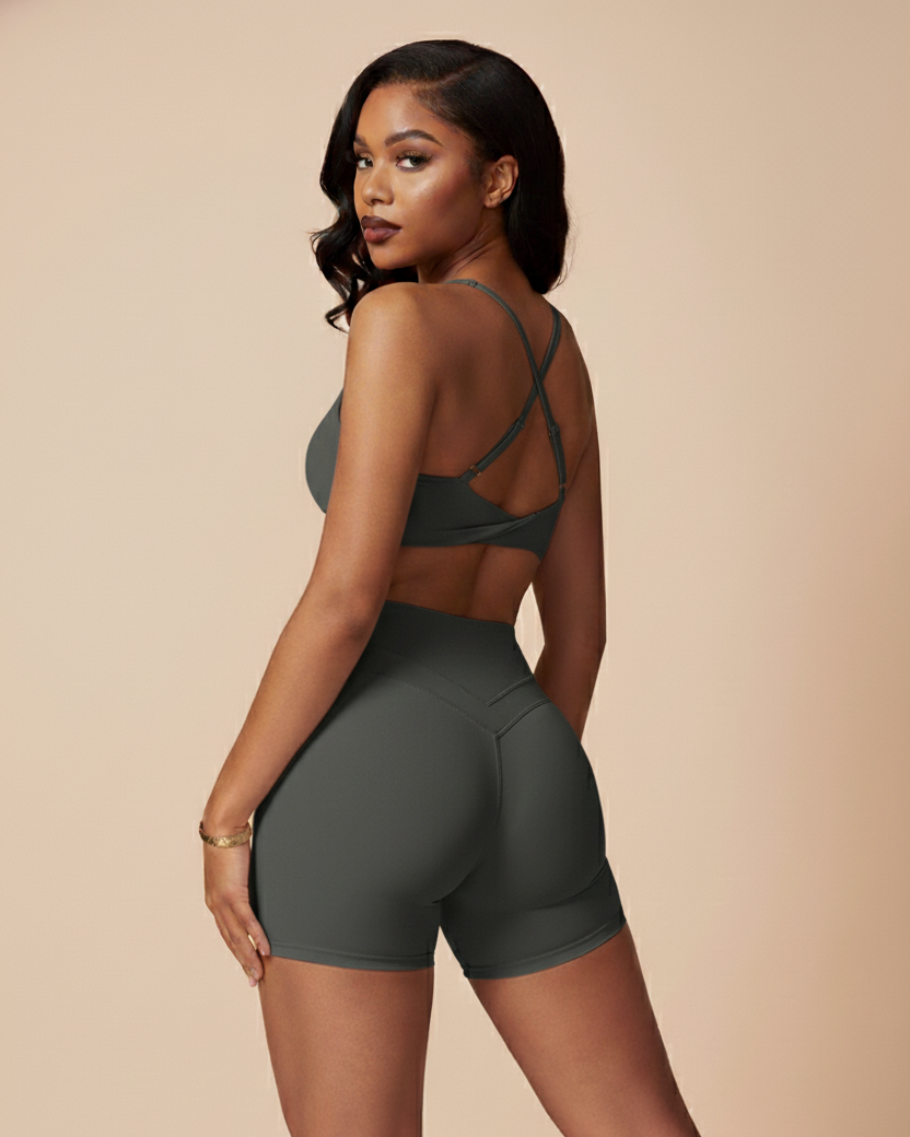 Woman wearing a grey sports bra and shorts set on a beige background