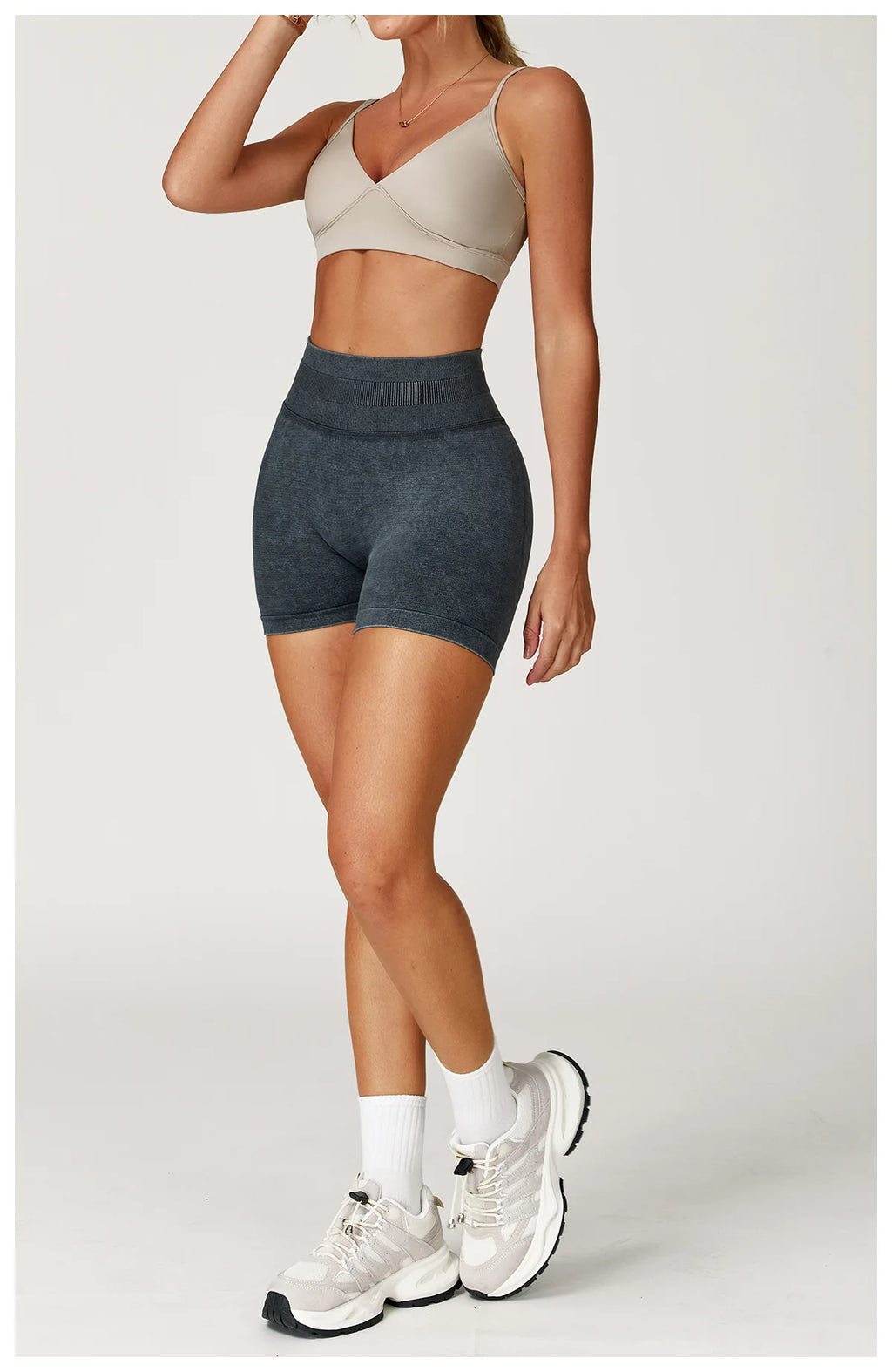 Xooie Fit acid wash workout shorts in dark gray worn with beige sports bra and white sneakers