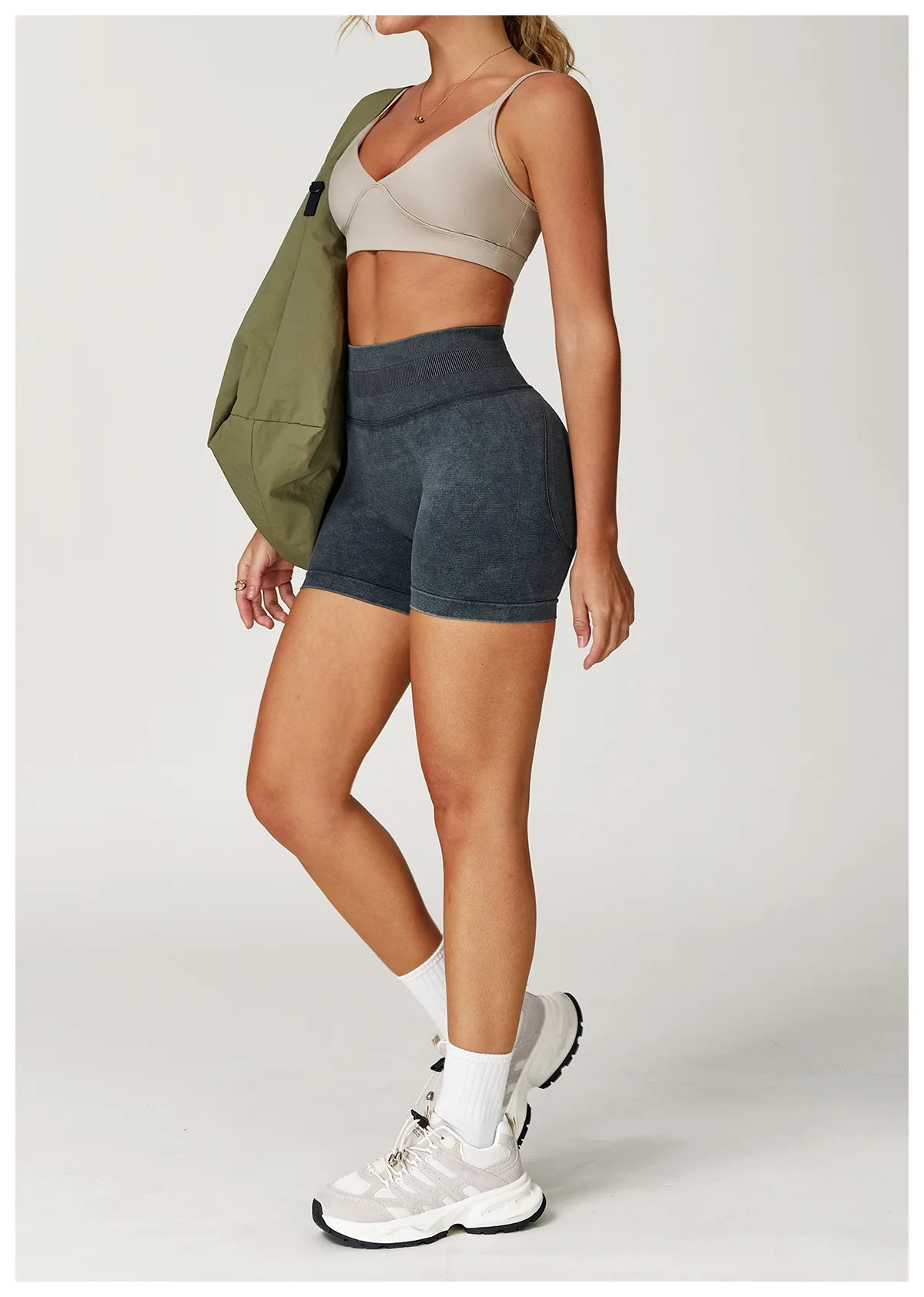 Xooie Fit acid wash workout shorts in dark gray worn with beige sports bra and white sneakers2