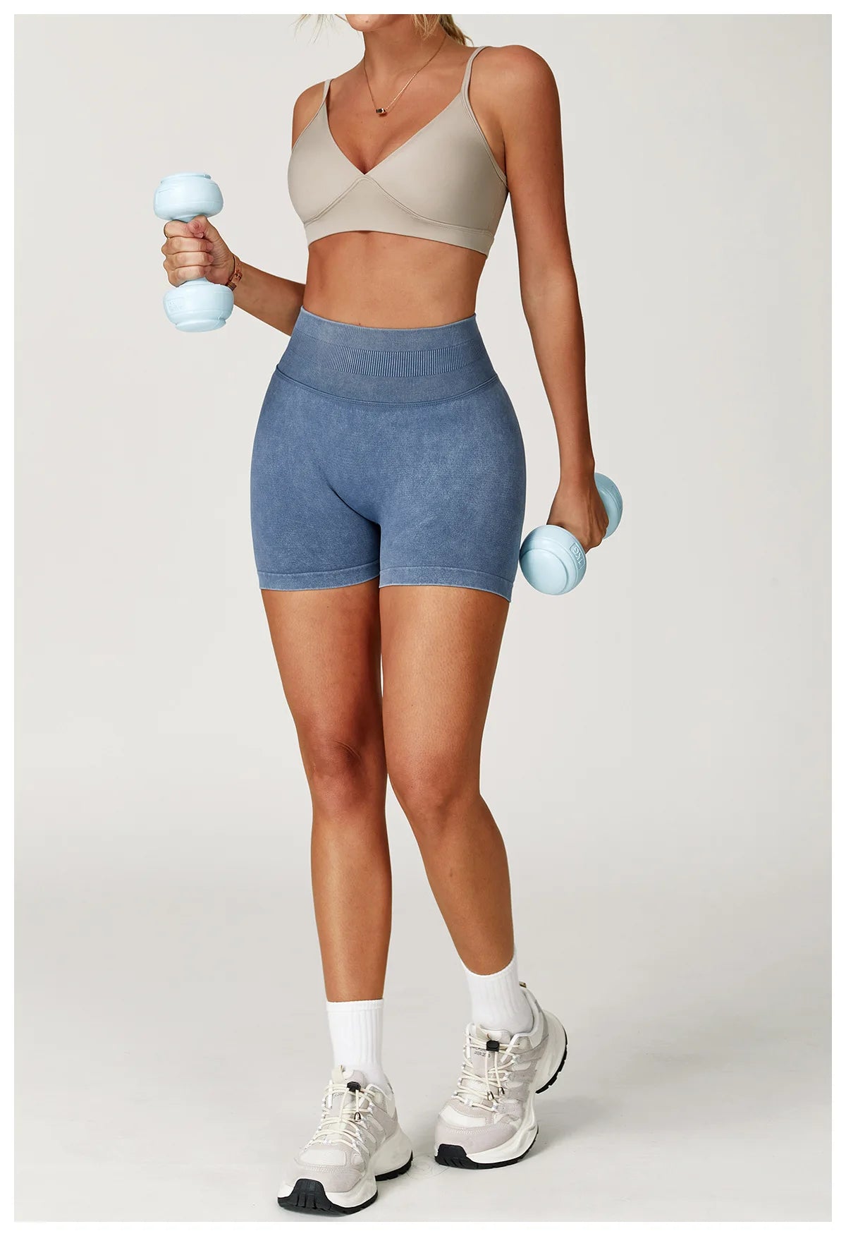 Xooie Fit acid wash workout shorts in blue worn by woman holding light blue dumbbells