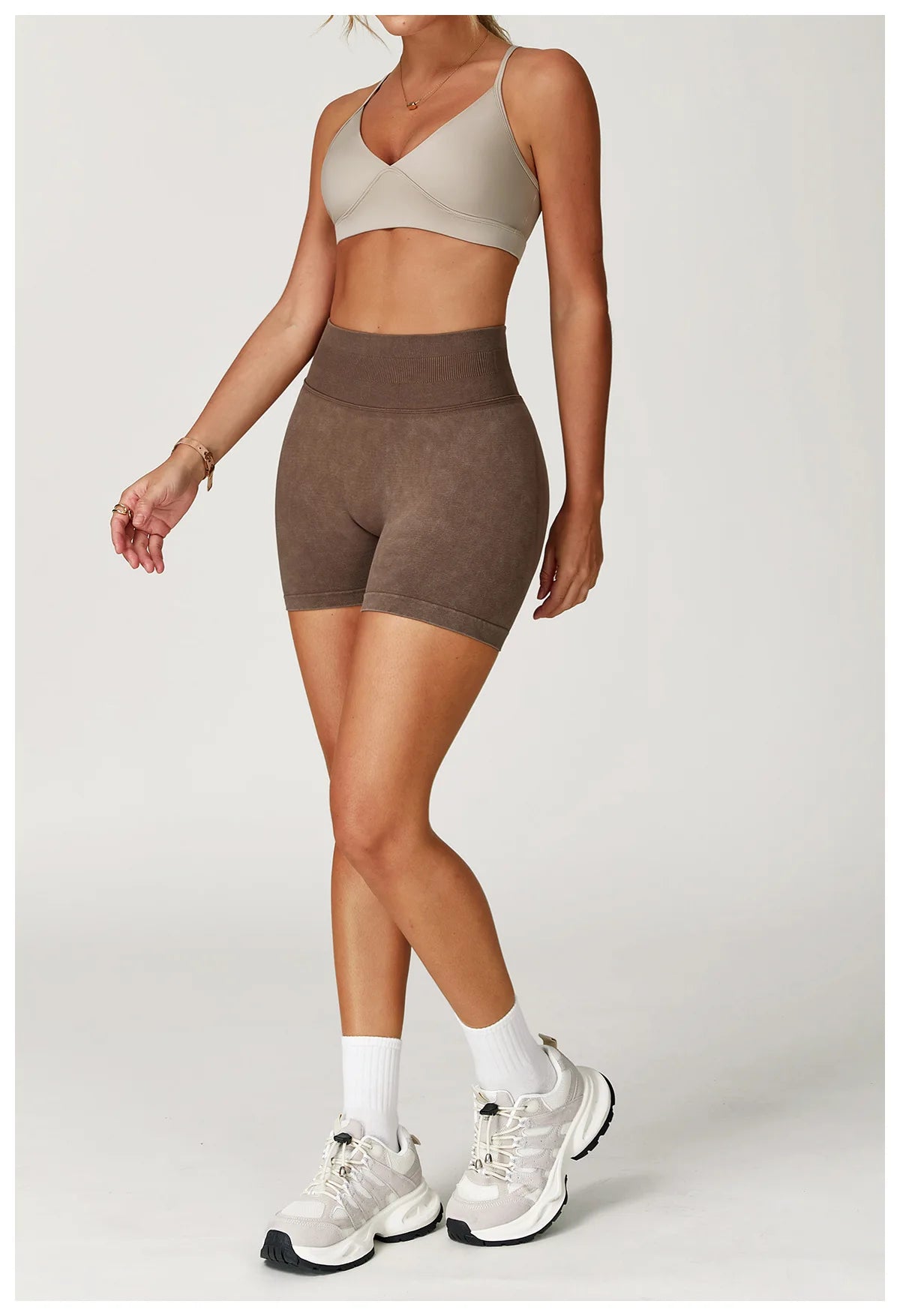 Xooie Fit acid wash workout shorts in brown worn with beige sports bra and white sneakers