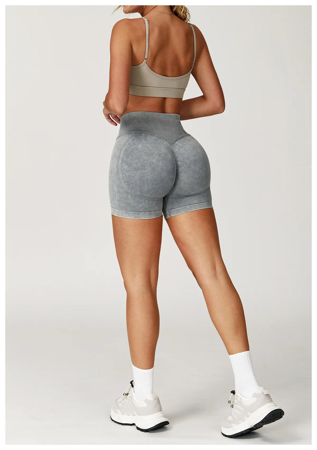 Xooie Fit acid wash workout shorts in gray modeled from back with sports bra and white sneakers