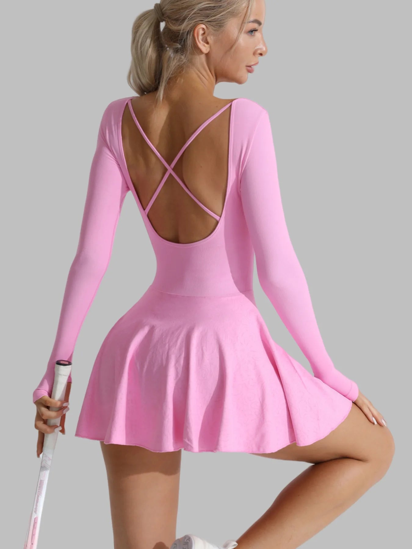 Pink long-sleeve active dress back view, open X-back straps, flared skirt and built-in shorts.