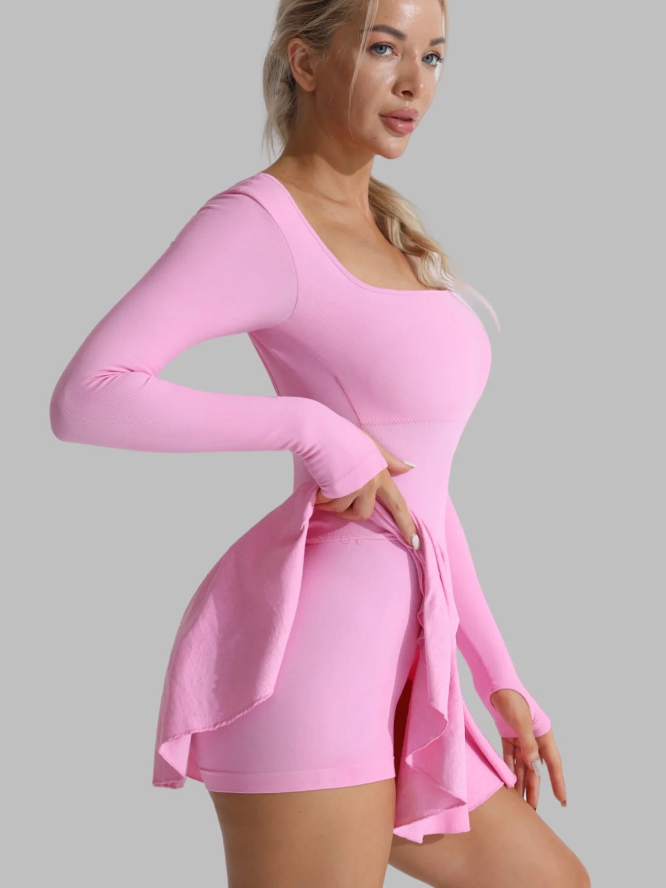 Pink long-sleeve active dress with flared skater skirt and built-in shorts, curved neckline.