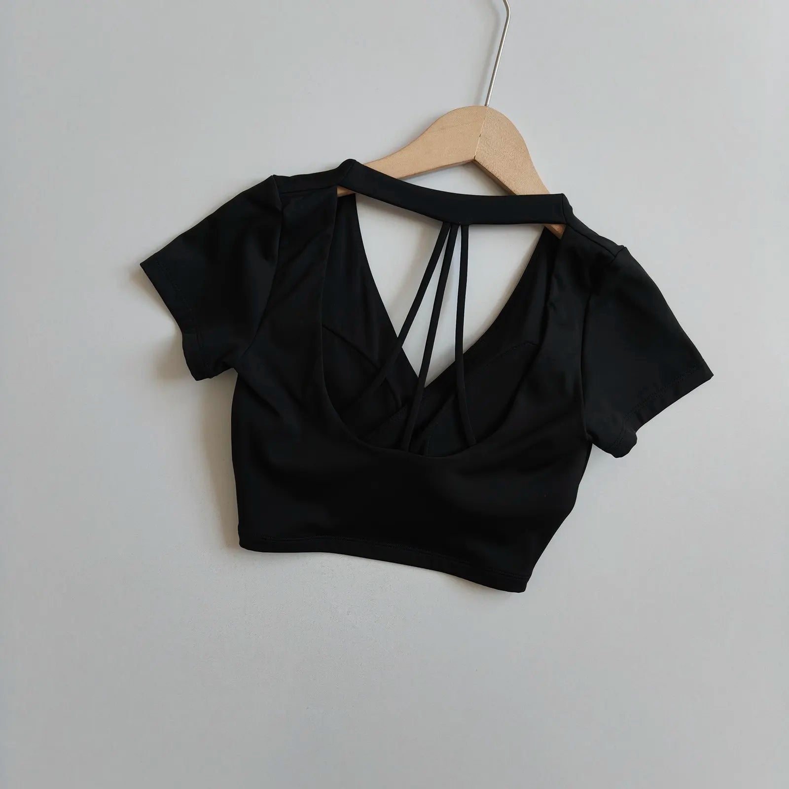 Black short-sleeve wrap crop top with crisscross open back and V-neck front