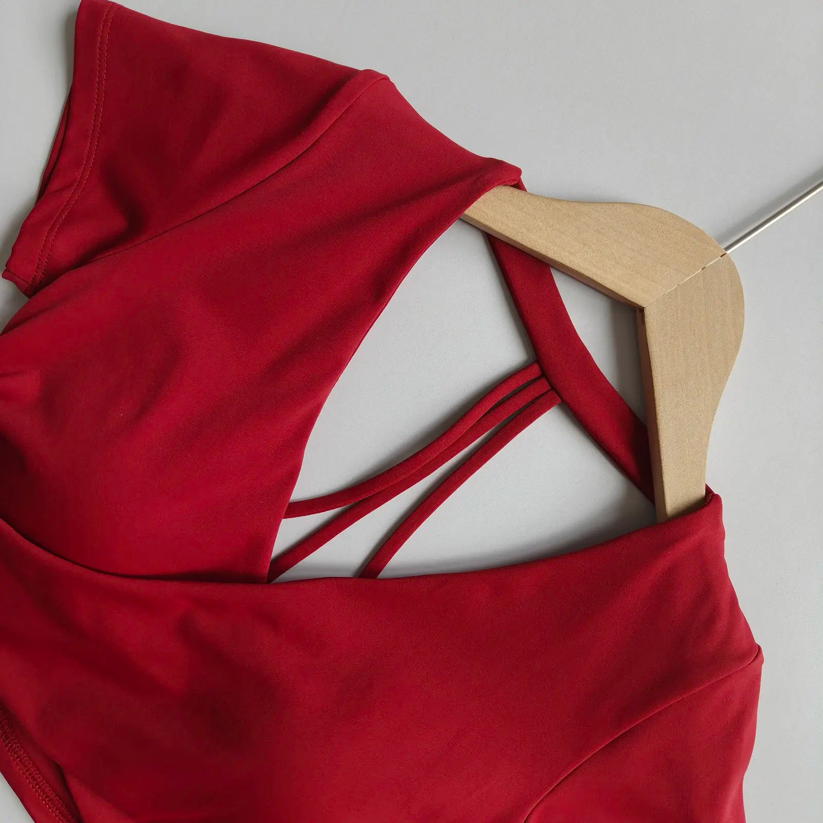 Wine red crisscross-back active crop top with V neckline on wooden hanger
