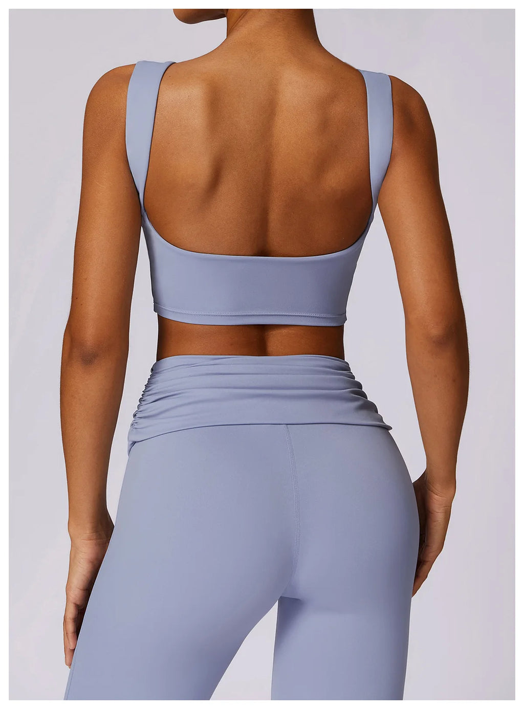 Light blue backless sports bra crop top with wide back straps and smooth finish.