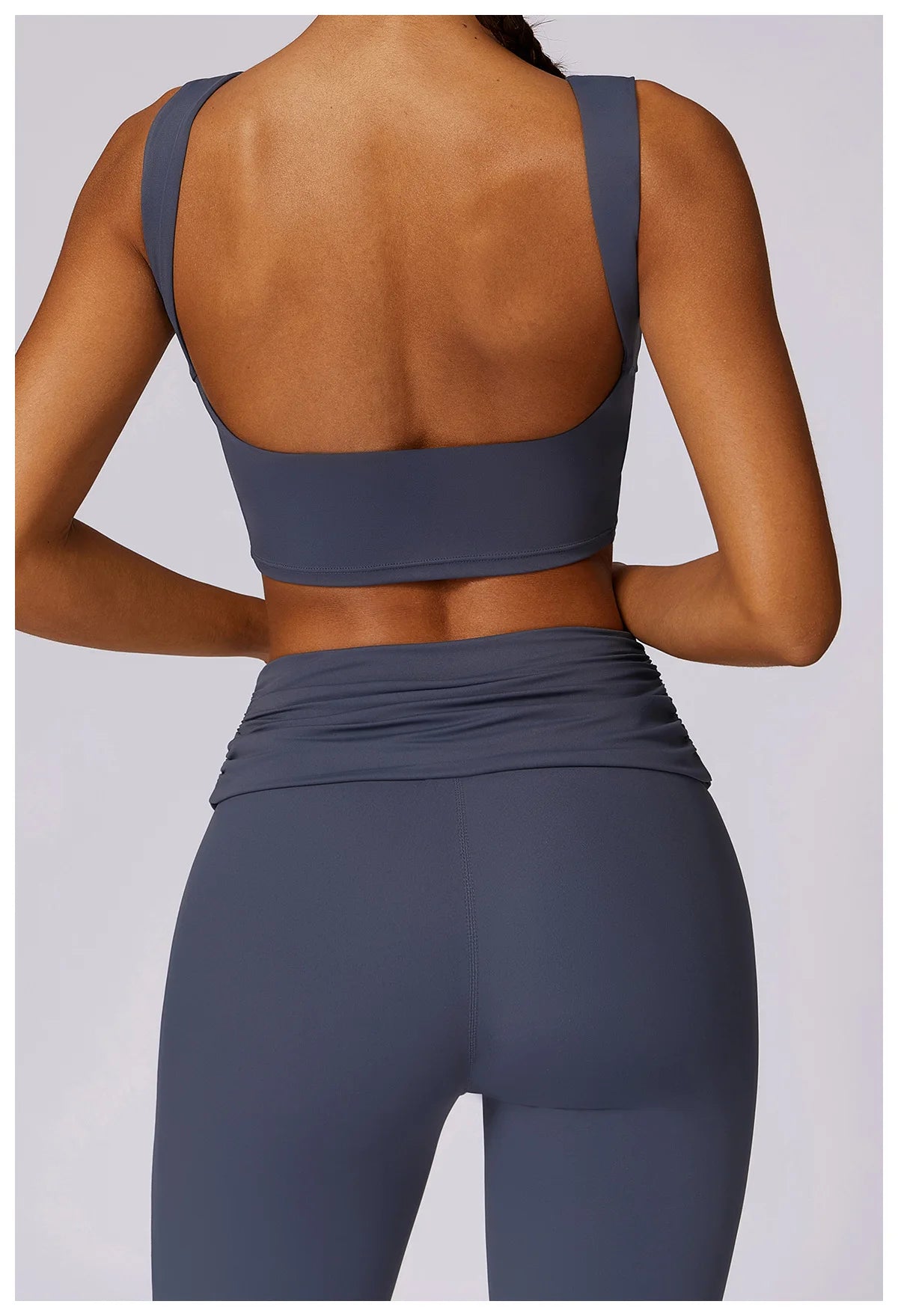 Women’s navy sports bra with open back and wide band, paired with ruched leggings