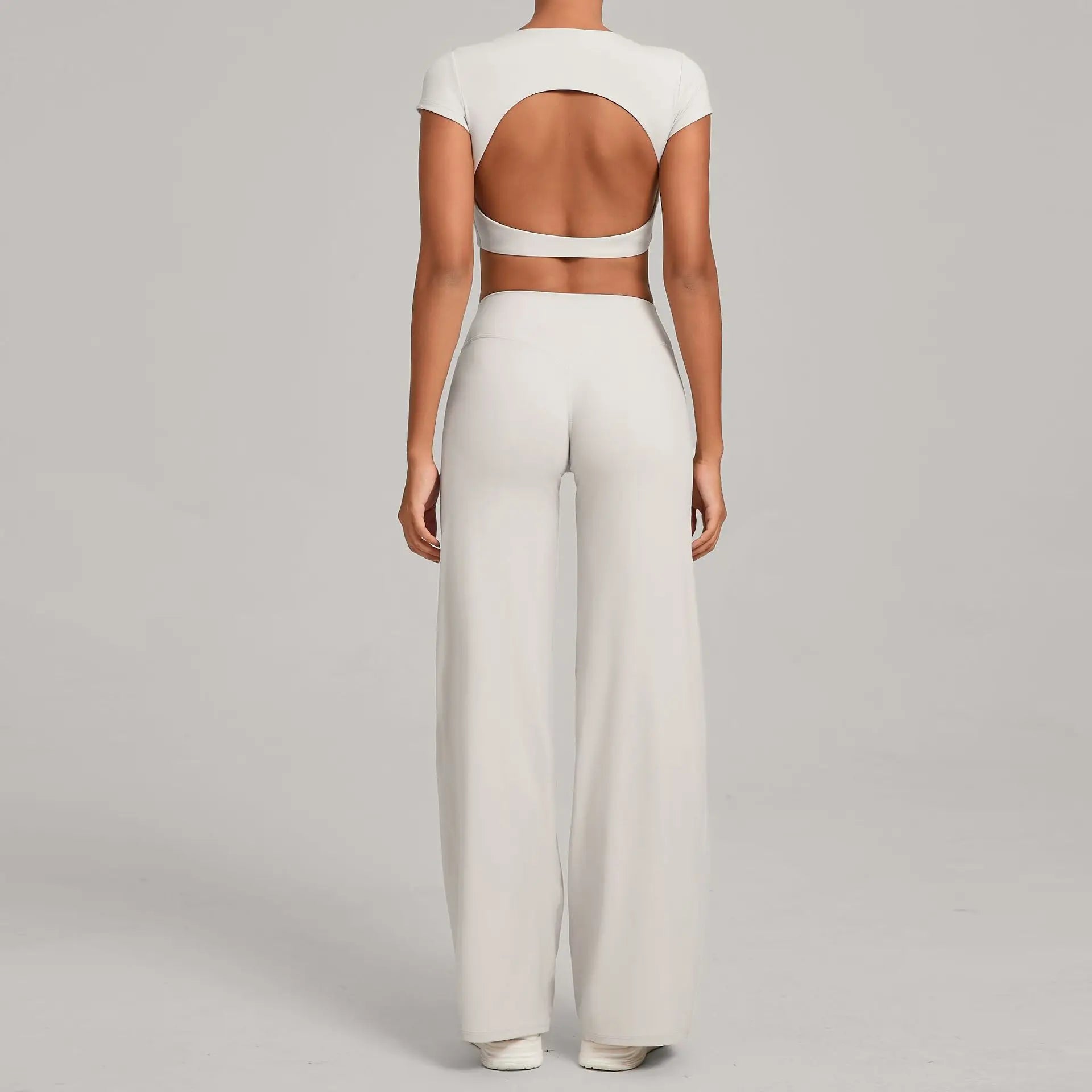 White backless crop top and flare pants set by Xooie Fit with a stylish open back design
