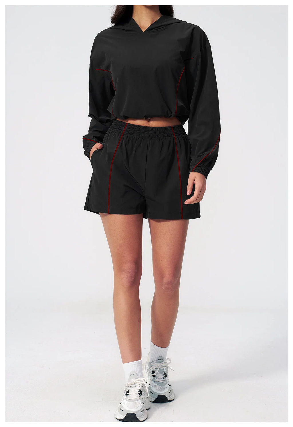 Women’s hooded sports set in black, jacket and shorts with red trim, side view
