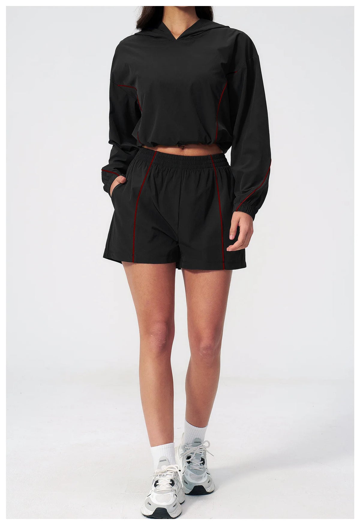 Women’s hooded sports set in black, jacket and shorts with red trim, side view