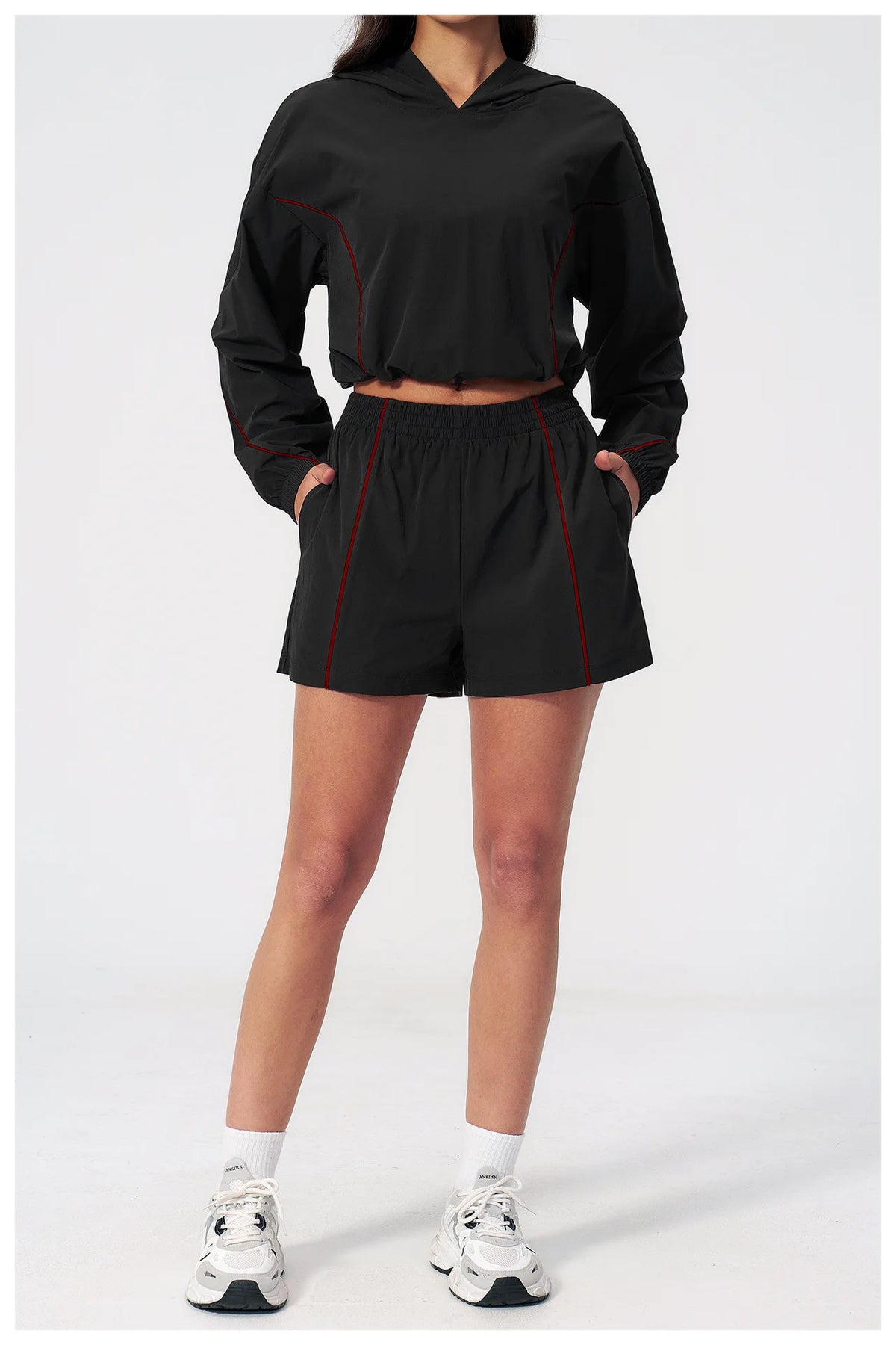 Women’s hooded sports set in black, front view cropped jacket and shorts with red piping